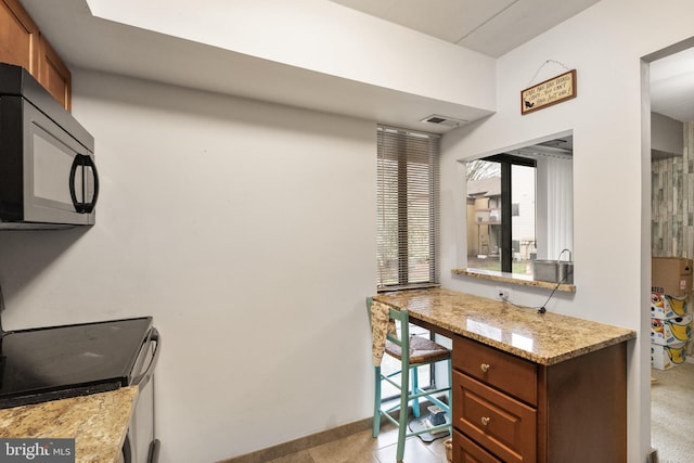 interior space featuring range with electric cooktop, baseboards, visible vents, and black microwave