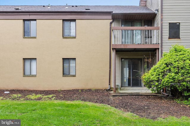 rear view of property with a balcony, stucco siding, and a shingled roof