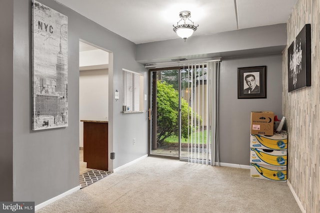 doorway to outside with carpet flooring and baseboards