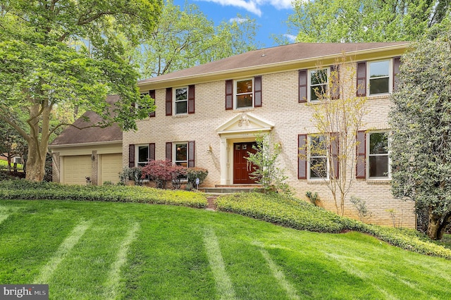 colonial-style house featuring brick siding, a garage, and a front yard