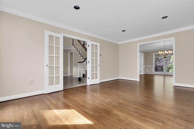 unfurnished living room featuring a chandelier, ornamental molding, french doors, and wood finished floors