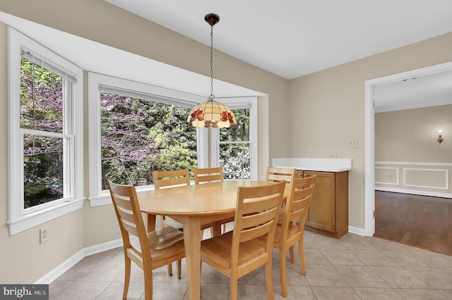 dining space with light tile patterned flooring, baseboards, and plenty of natural light