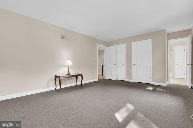 unfurnished bedroom featuring baseboards, carpet, and visible vents