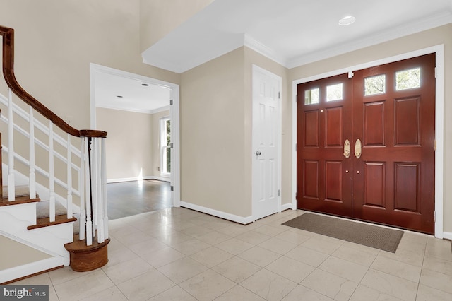 tiled foyer with crown molding, baseboards, and stairs
