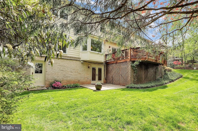back of property featuring brick siding, a deck, a patio area, french doors, and a yard