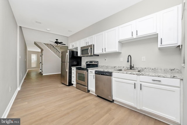 2828 Woodbrook Ave, Baltimore, MD 21217 - kitchen with stainless steel appliances, white cabinetry, a sink, light wood-style floors, and ceiling fan