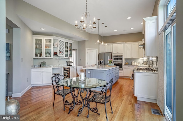 dining room with beverage cooler, a notable chandelier, light wood-type flooring, baseboards, and recessed lighting