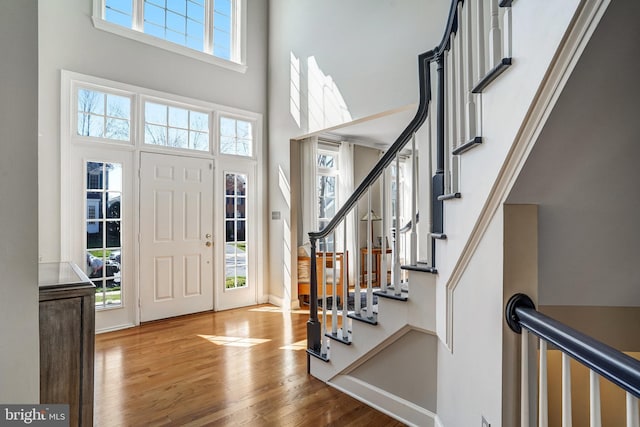 entryway with baseboards, stairway, a high ceiling, and wood finished floors