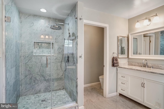 bathroom with a shower stall, toilet, vanity, and baseboards