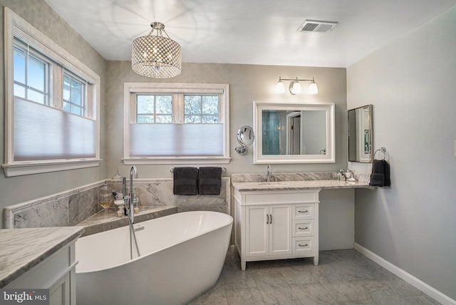 bathroom featuring a freestanding bath, visible vents, baseboards, marble finish floor, and vanity