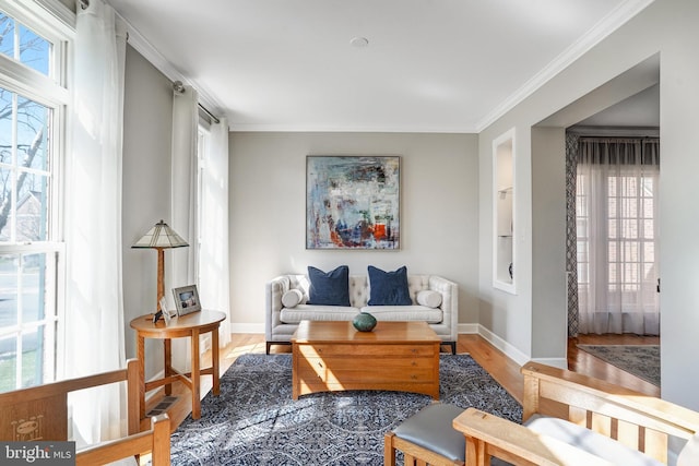 living room featuring baseboards, ornamental molding, built in features, and wood finished floors