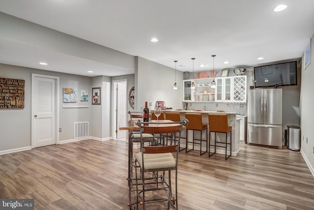 dining area featuring light wood-type flooring, visible vents, indoor wet bar, and recessed lighting