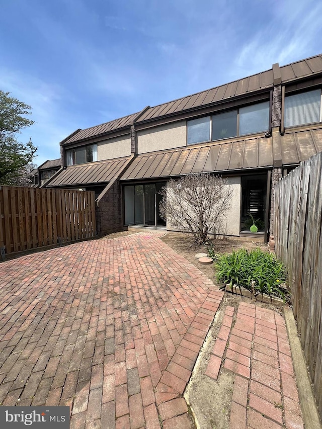 2357 Nutmeg Ter, Baltimore, MD 21209 - view of property featuring a standing seam roof, metal roof, fence, a patio, and stucco siding
