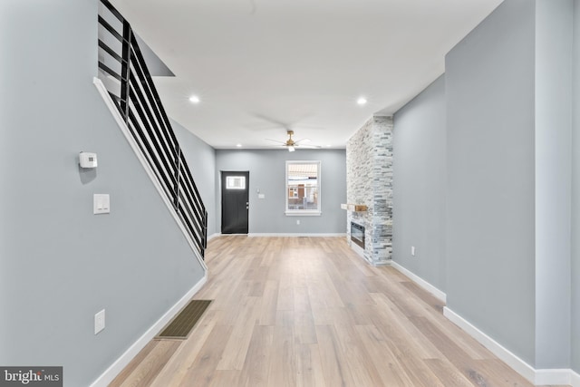 unfurnished living room with visible vents, stairs, a fireplace, a ceiling fan, and light wood-type flooring
