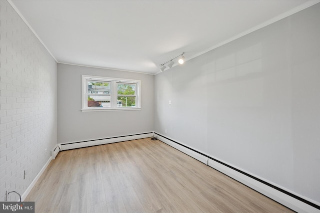 spare room with track lighting, brick wall, ornamental molding, and wood finished floors