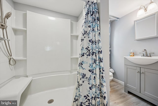 bathroom featuring vanity, wood finished floors, curtained shower, toilet, and baseboards