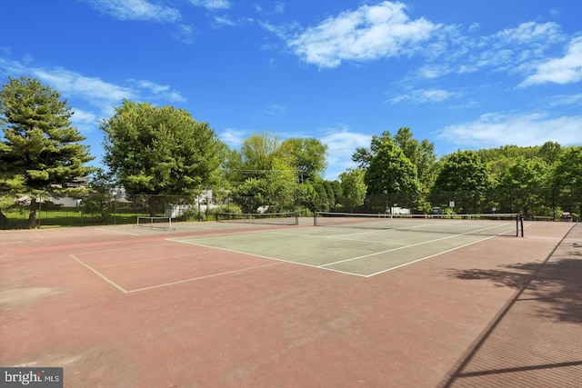 view of tennis court featuring community basketball court and fence
