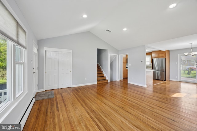 unfurnished living room featuring baseboard heating, vaulted ceiling, light wood-type flooring, a notable chandelier, and recessed lighting