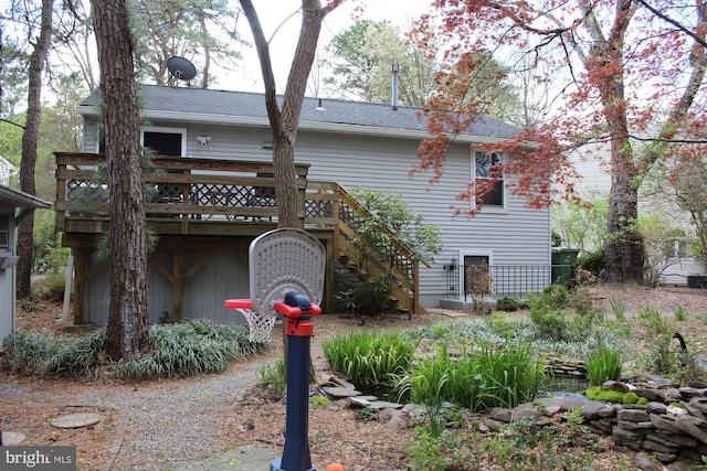 rear view of property with stairway, a wooden deck, and a shingled roof