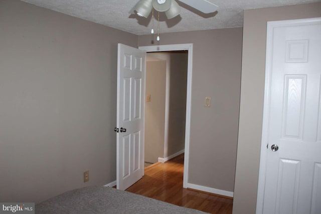 bedroom featuring baseboards, a textured ceiling, and wood finished floors