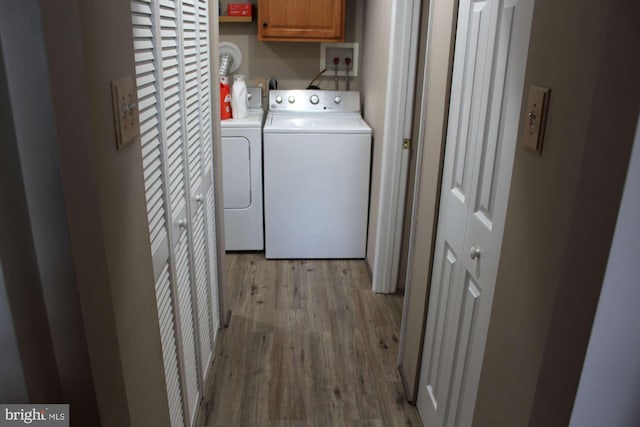 clothes washing area featuring cabinet space, independent washer and dryer, and light wood-style floors