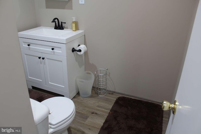half bath with vanity, toilet, and wood finished floors