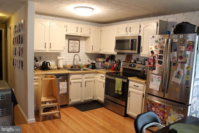 kitchen with tasteful backsplash, a sink, light countertops, stainless steel appliances, and light wood-style flooring