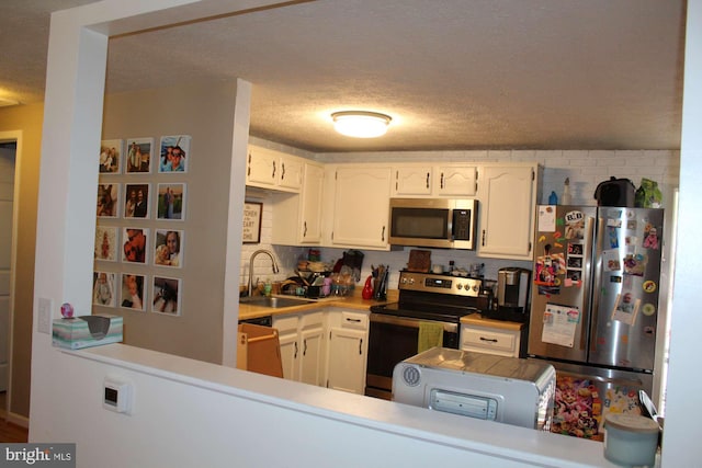 kitchen featuring a sink, light countertops, appliances with stainless steel finishes, white cabinetry, and backsplash