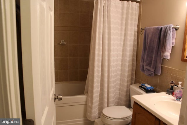 full bath featuring tile walls, toilet, shower / bathtub combination with curtain, and vanity