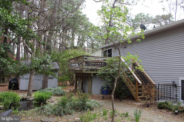 back of house with a storage shed, an outbuilding, a wooden deck, and stairs