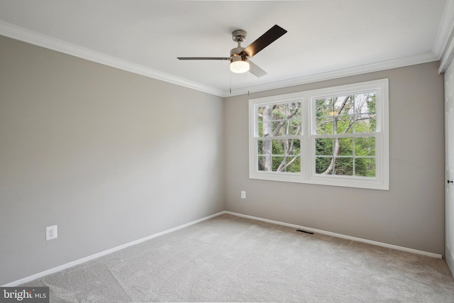 carpeted spare room featuring visible vents, ornamental molding, baseboards, and ceiling fan
