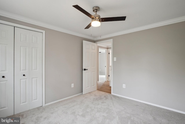 unfurnished bedroom featuring carpet floors, crown molding, a closet, and baseboards
