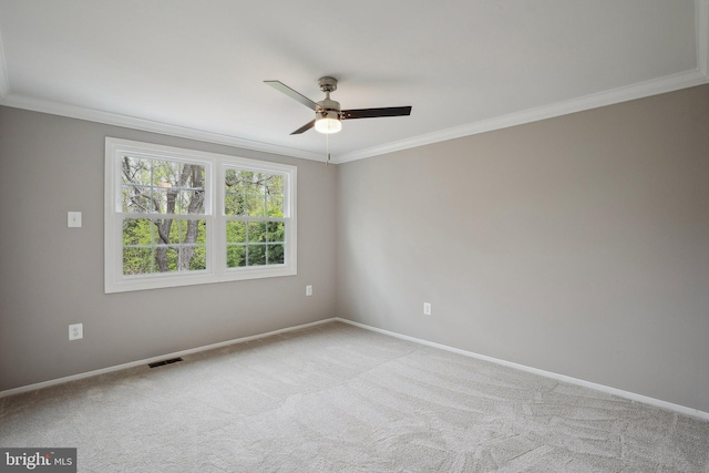carpeted empty room featuring baseboards, ornamental molding, visible vents, and a ceiling fan