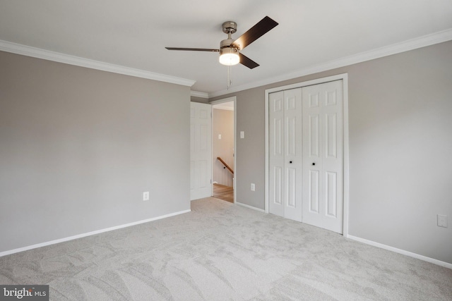 unfurnished bedroom featuring carpet floors, crown molding, baseboards, and a closet