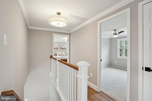 hallway featuring baseboards, an upstairs landing, wood finished floors, and crown molding