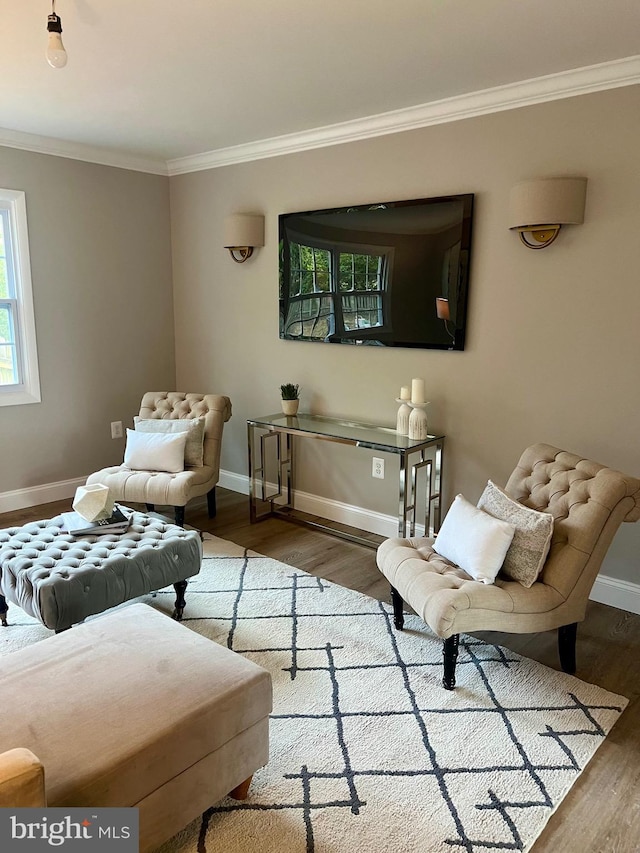 living area with baseboards, ornamental molding, and wood finished floors