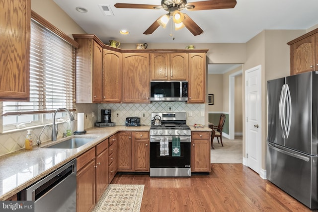 kitchen featuring visible vents, a sink, ceiling fan, appliances with stainless steel finishes, and light wood-style flooring