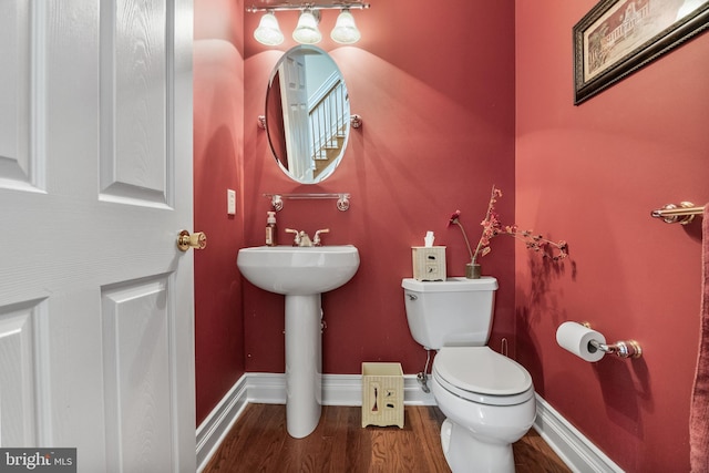 bathroom with baseboards, toilet, and wood finished floors