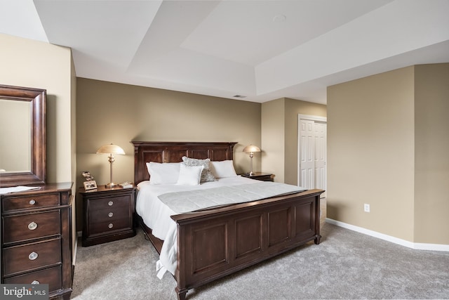 bedroom featuring visible vents, baseboards, a closet, a tray ceiling, and light carpet