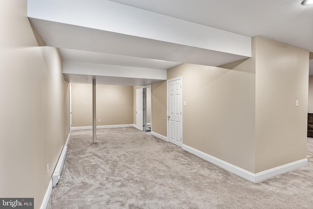 finished basement featuring a baseboard heating unit, baseboards, and carpet
