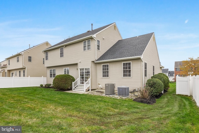 rear view of property with entry steps, a yard, a fenced backyard, and central AC unit