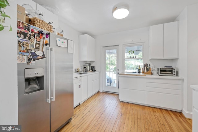 kitchen featuring white dishwasher, light countertops, light wood-type flooring, and high end fridge