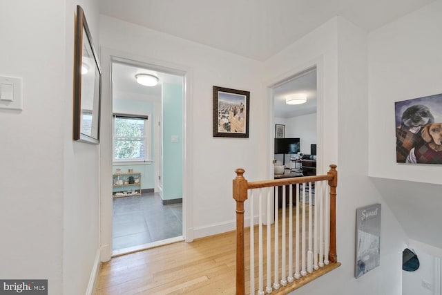 hallway with baseboards, an upstairs landing, and wood finished floors