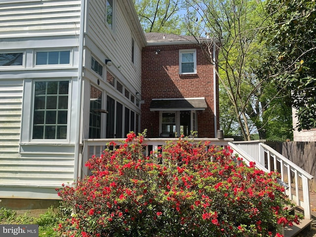 back of property with brick siding, fence, and a wooden deck