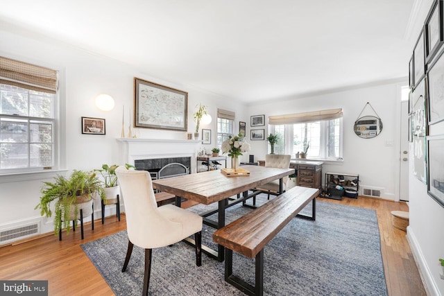 dining space with baseboards, visible vents, light wood-type flooring, and a fireplace