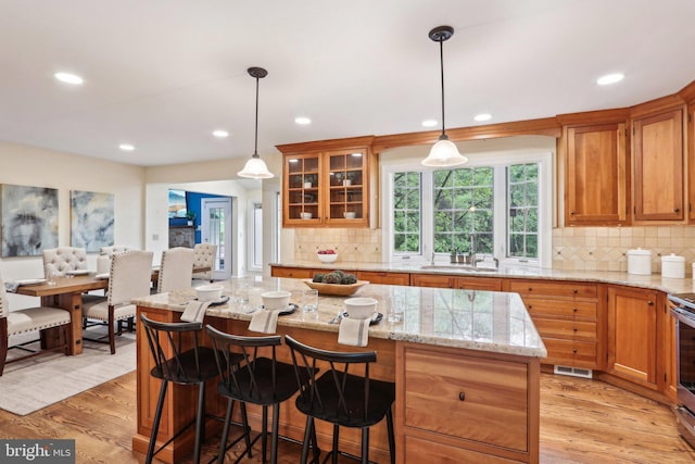 kitchen featuring a sink, recessed lighting, backsplash, light wood-style floors, and a center island