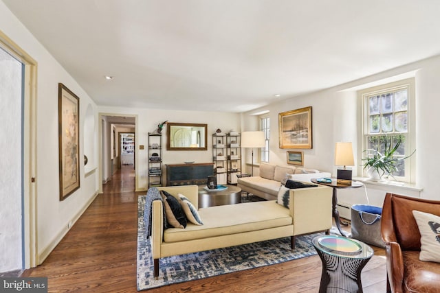 living area with dark wood finished floors, plenty of natural light, baseboard heating, and recessed lighting