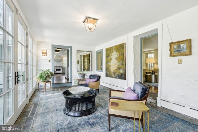 sunroom featuring a baseboard heating unit and french doors
