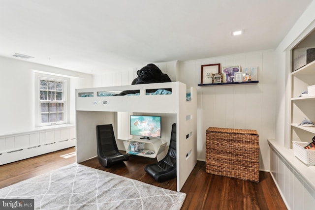 bedroom featuring wood finished floors and a baseboard heating unit