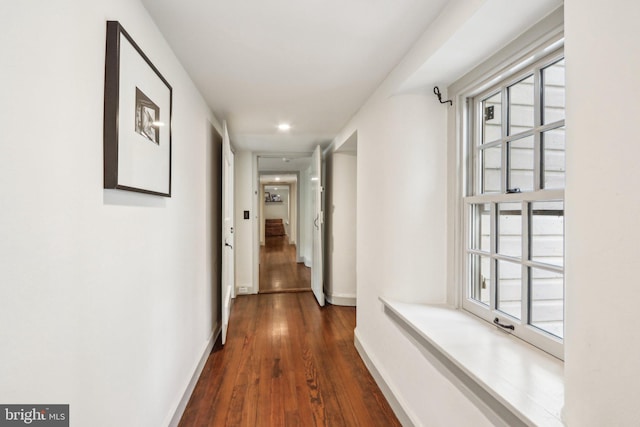 hall with dark wood finished floors, baseboards, recessed lighting, and plenty of natural light